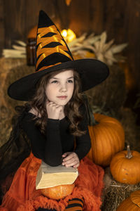 Portrait of woman wearing hat standing by pumpkin