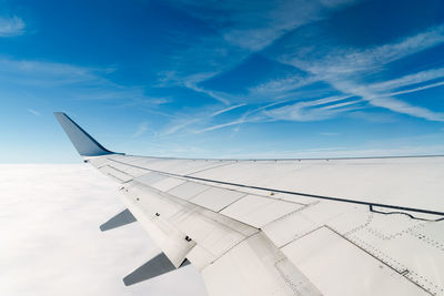 Cropped image of airplane wing flying against sky