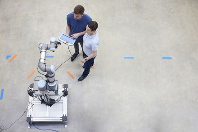 Engineers testing modern machine standing on floor in industry