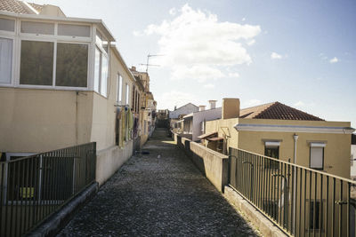 Footpath amidst buildings against sky