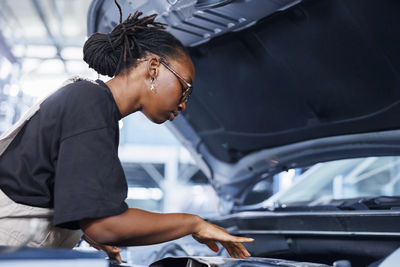 Side view of young man repairing car