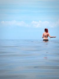 Woman in sea against sky