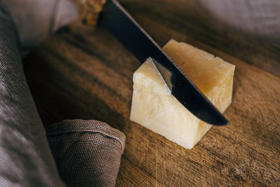 High angle view of knife cutting italian cheese on wooden board