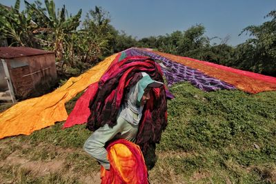 Man carrying textile while walking on field