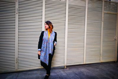 Portrait of young woman standing against brick wall