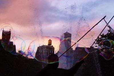 Digital composite image of bubbles against sky in city during sunset