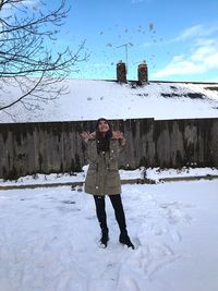 Full length portrait of woman standing on snow field against sky