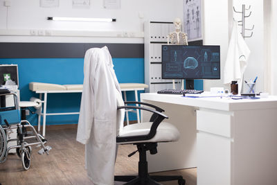 Rear view of female doctor using mobile phone in office
