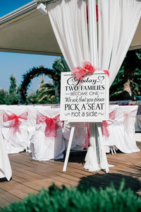 Information sign by decorated chairs at wedding ceremony