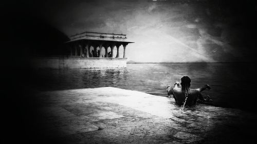 Rear view of women sitting on water against sky