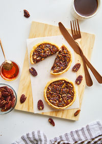 Homemade pecan pie served on wood board, white background with setting and ingredient, top view