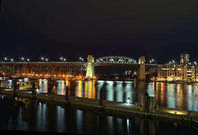 Illuminated bridge over river against sky at night