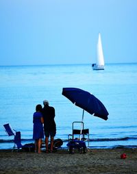 Rear view of people on beach against clear sky