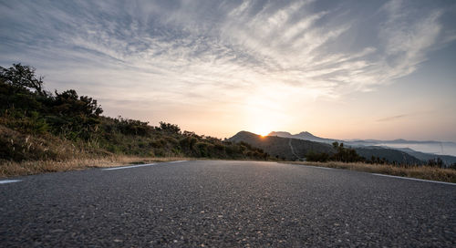 Surface level of road against sky during sunset