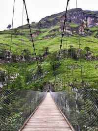 Footbridge amidst mountains against sky