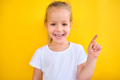 Portrait of young woman against yellow background