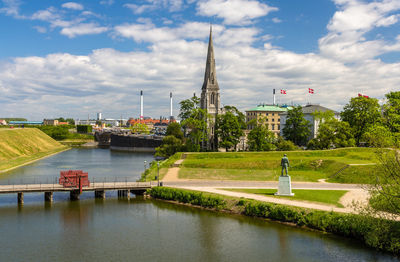 View of river and buildings against cloudy sky