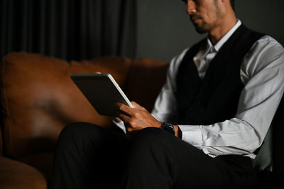 Midsection of businessman using digital tablet at office