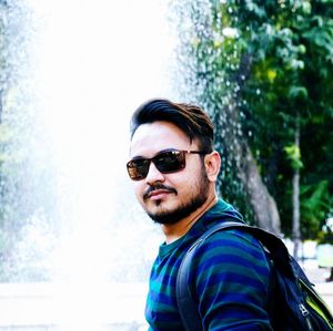 Side view portrait of young man wearing sunglasses against fountain