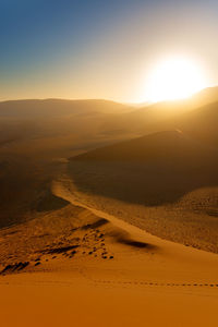 Scenic view of desert against clear sky during sunset