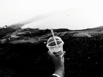 Person holding ice cream against mountain and sky