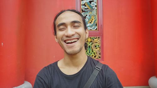 Close-up of smiling young man against red wall