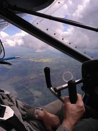Midsection of man sitting in airplane against sky