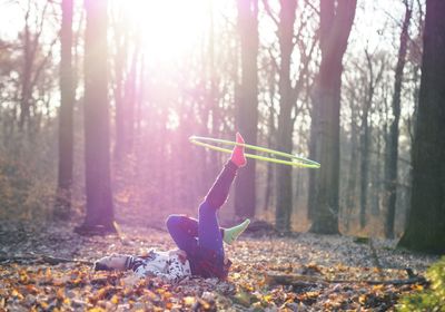 Woman playing with plastic hoop while lying on field at park