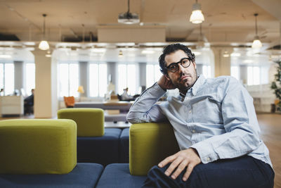 Portrait of mature man sitting on couch at corridor