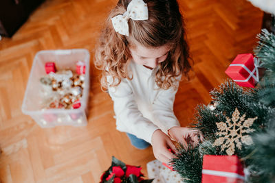 High angle view of cute girl decorating christmas tree at home