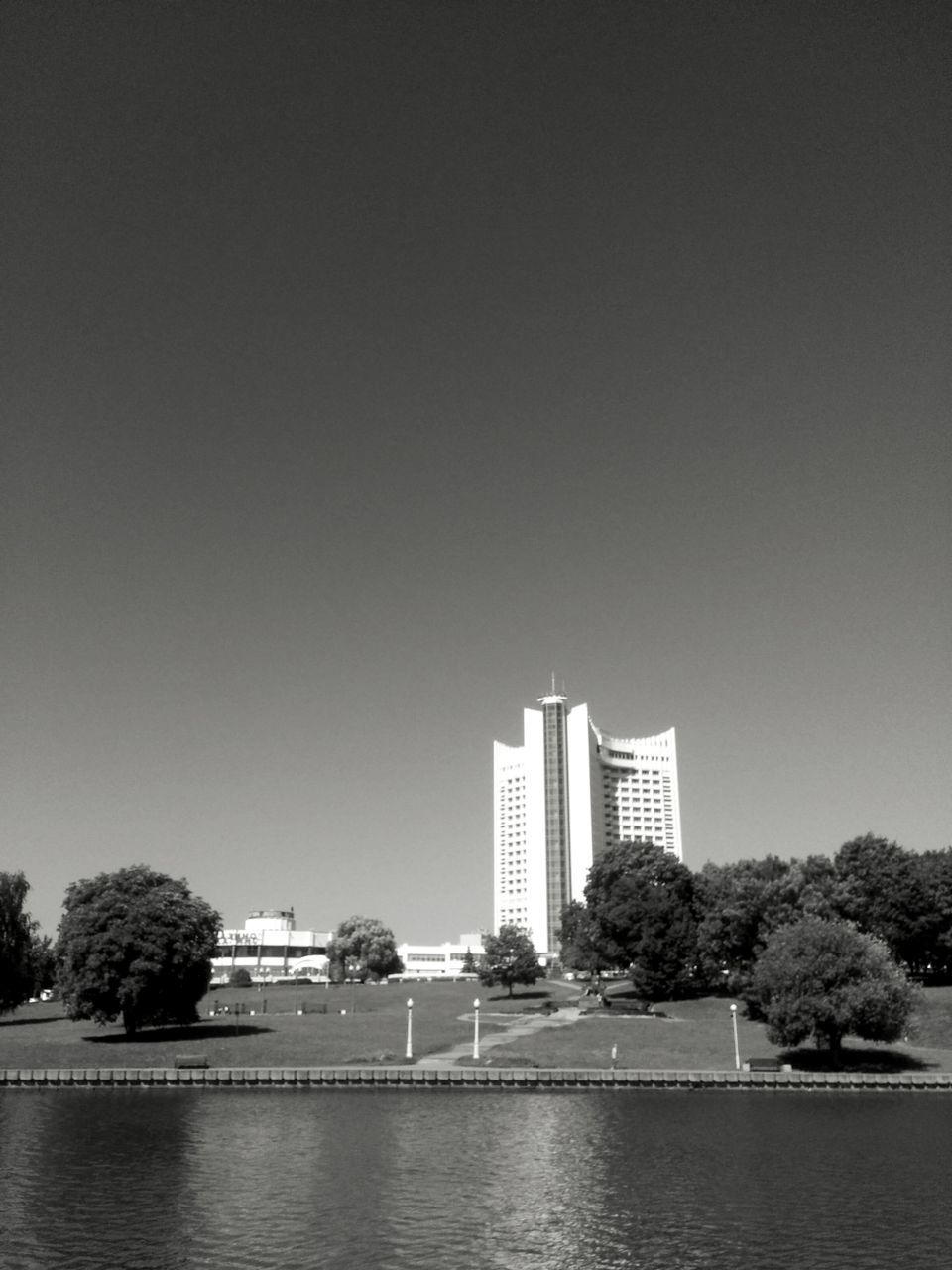 architecture, built structure, tree, clear sky, building exterior, copy space, skyscraper, water, modern, waterfront, travel destinations, city, sky, growth, day, outdoors, no people, nature, urban skyline