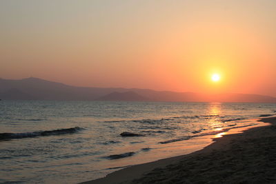 Scenic view of beach against clear sky during sunset