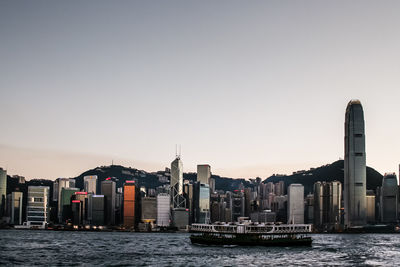 Ferry sailing on victoria harbor against two international finance center at sunset