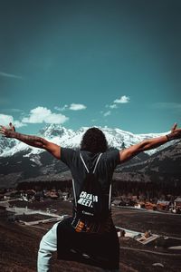 Rear view of woman with arms outstretched against sky