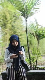 Young woman using mobile phone while sitting in park