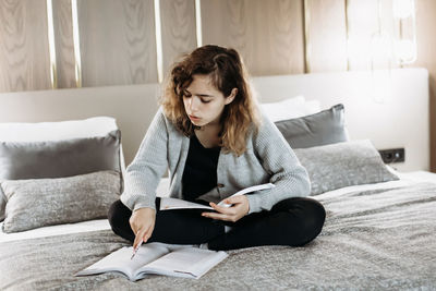 Teenager girl studying on bed at home. student doing homework