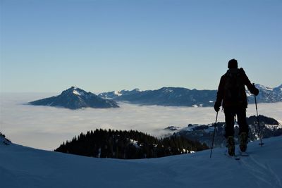 Rear view of man looking at mountains against sky