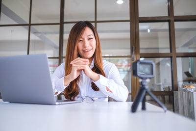 Portrait of smiling young woman using phone