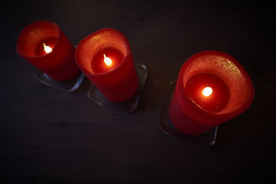 Close-up of lit tea light candle in darkroom