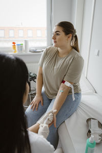 Female patient doing medical checkup while sitting on bed in clinic