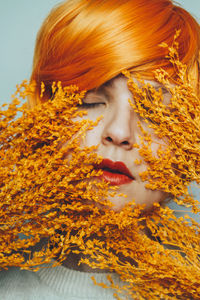 Close-up portrait of young woman with autumn leaves