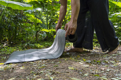 Young latin man arranging his yoga mat, inside a forest on a plain, direct contact with nature, 