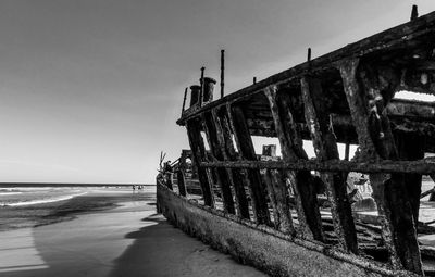 Abandoned shipwreck on shore at beach against sky