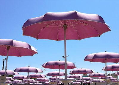 Low angle view of beach umbrellas against clear blue sky