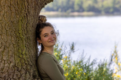 Young brunette woman sitting in green forest enjoys the silence and beauty of nature