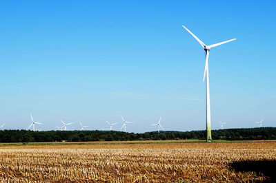 Wind turbines on field against clear sky