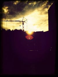 Low angle view of silhouette electricity pylon against sky during sunset