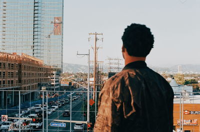 Rear view of man standing against buildings in city