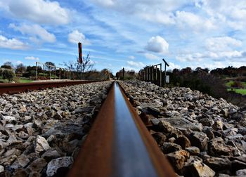 Close-up of railroad track amidst gravels against sky