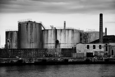 Factory by sea against sky